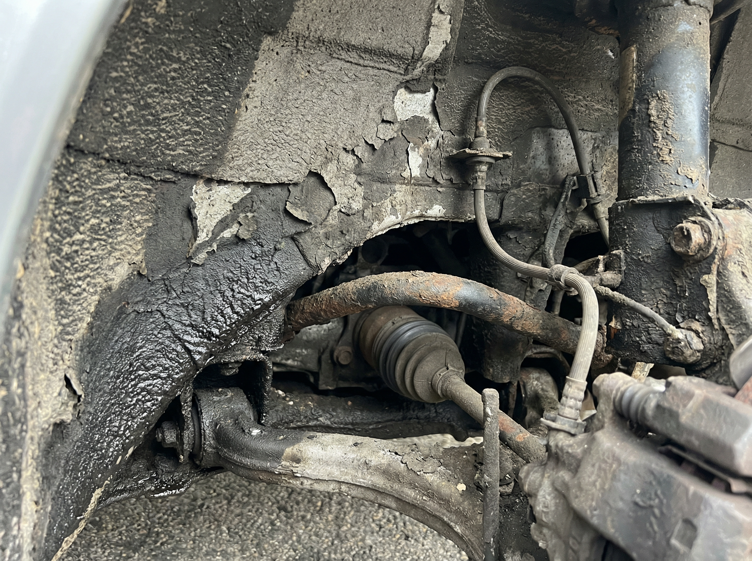 Porsche 964 wheel well before dry ice blasting — 30 years of road tar and contamination