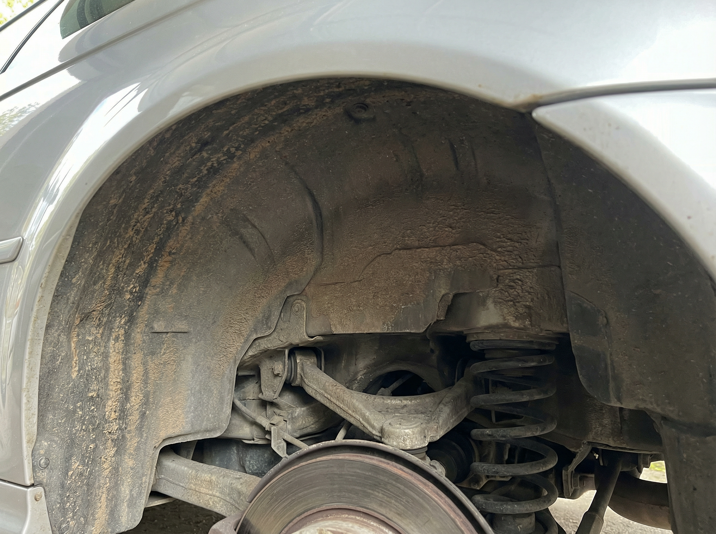 BMW E46 M3 wheel well before dry ice blasting — undercoating and dirt-packed suspension