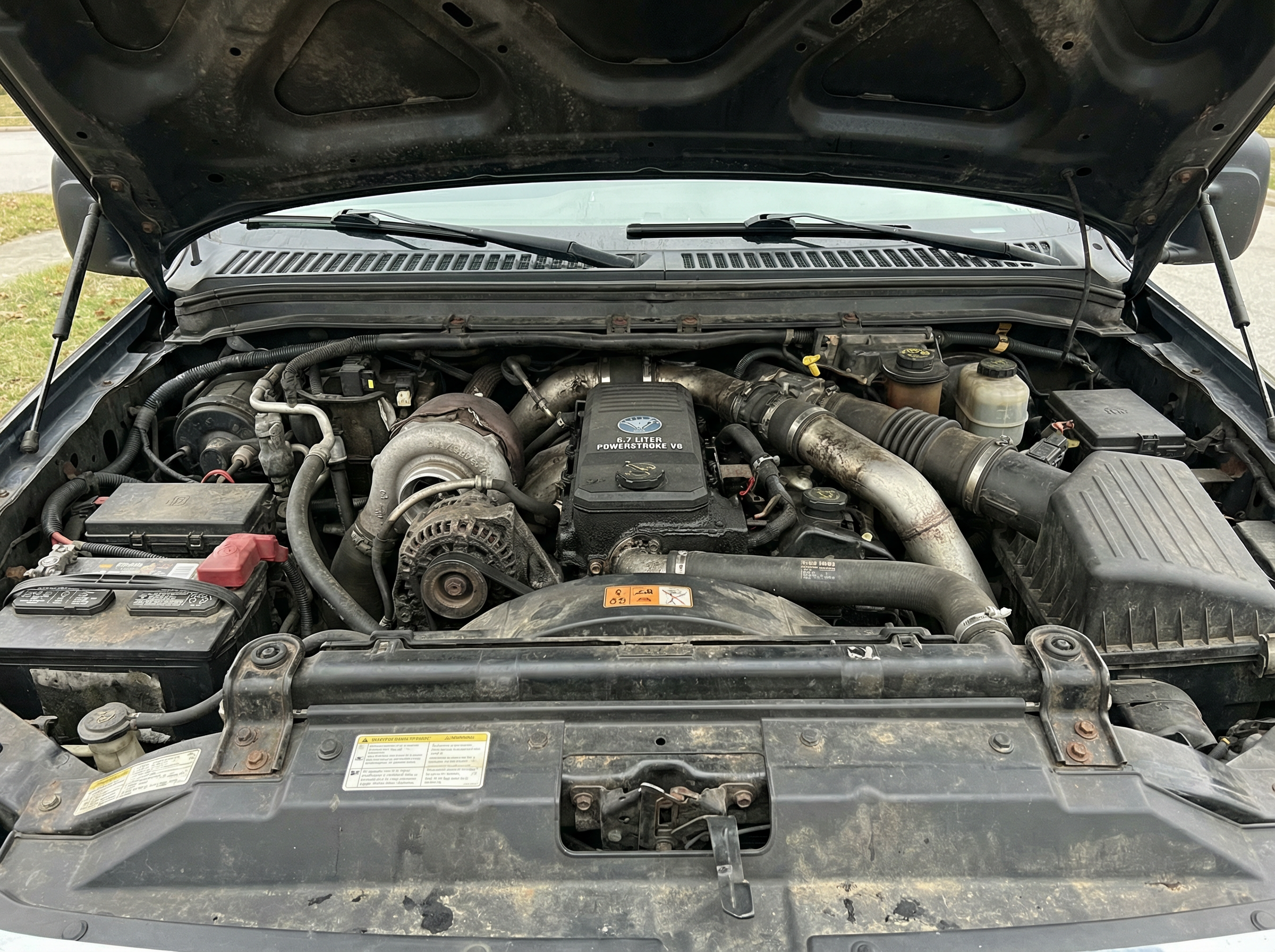 Ford F-250 diesel engine bay before dry ice blasting — heavy oil and road contamination