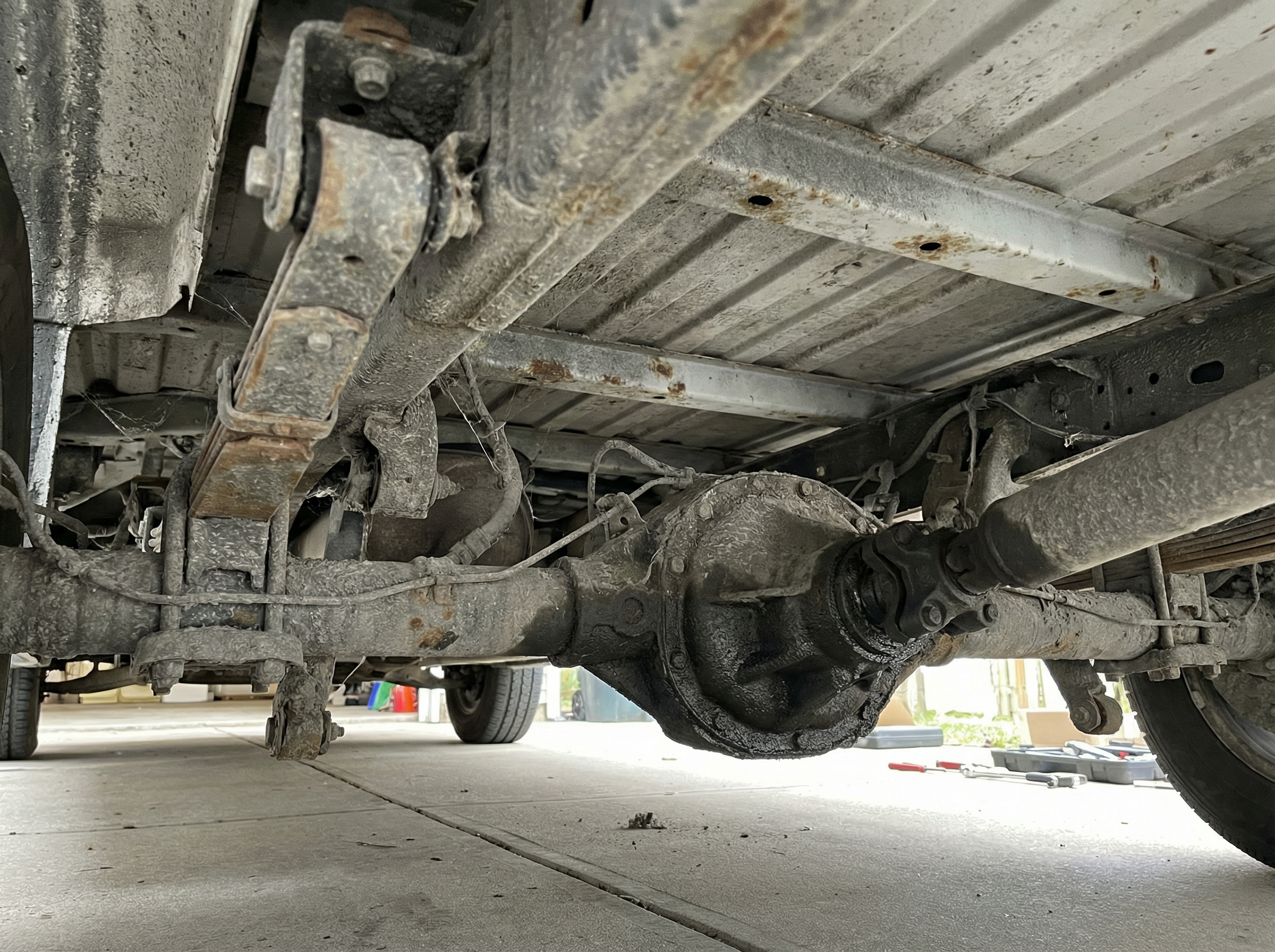 Commercial fleet van underbody before dry ice blasting — heavy contamination buildup